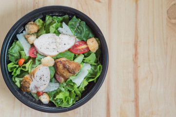 Organic mixed green salad with chicken in a transparent plastic plates on  wooden table very tasty