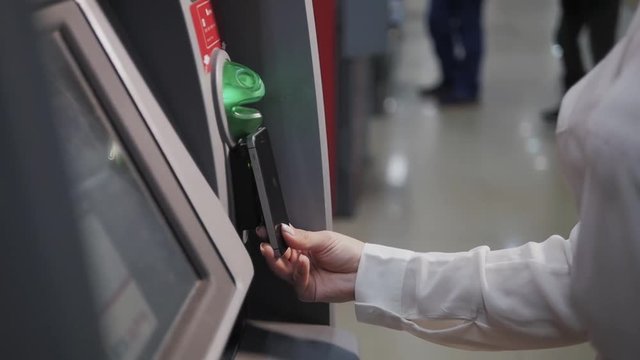 Smiling young woman withdrawing money from ATM using phone contactless pay