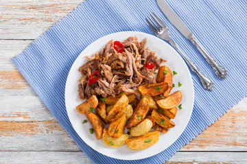 pulled slow-cooked meat grilled in oven with fried potato wedges