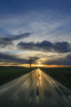 Sunrise reflected on the countryside wet road after the rain.Italy,Apulia.The beginning of a new day:vanishing point.