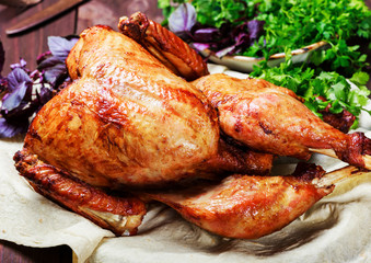 Roasted Turkey. Thanksgiving table served with turkey, decorated with greens and basil on dark wooden background. Homemade roasted chicken. Christmas holiday dinner. Top view