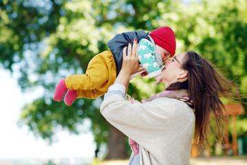 Obraz premium Young and happy mother cares for her young son and played with him in the summer in the park. family Concept
