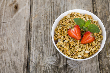 Granola with strawberry on a wooden table. Healthy eating for br