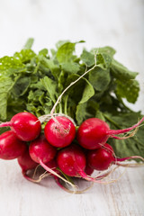 Ripe red radish with leaves on a wooden table close-up. Fresh ve
