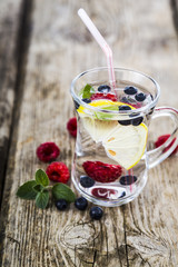 Homemade lemonade with fresh berries on a wooden table.Cocktail