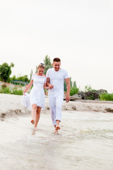 Beautiful couple in white clothes walking on the sea