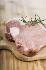 Raw pork with rosemary on a wooden board on the table. Cooking f