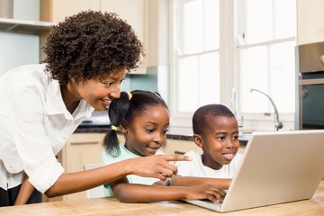 Fototapeta premium Happy family using laptop in the kitchen
