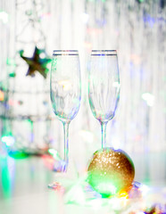 New Year's Eve champagne glasses with a ball and toys on the background of garlands
