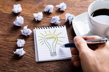 Person Drawing Lighting Bulb On Notepad