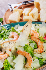Shrimp salad with parmesan cheese, croutons, tomatoes, mixed greens, lettuce and glass of wine on wooden background. Healthy food. Top view