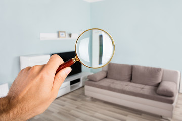 Person Checking Living Room Using Magnifying Glass