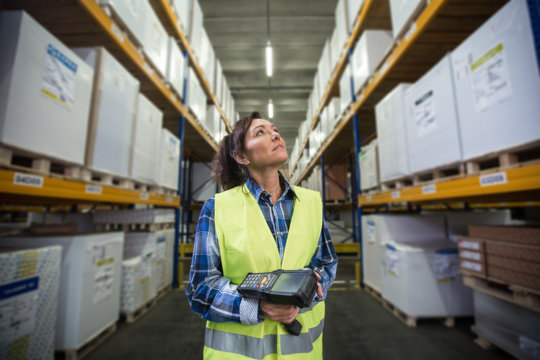 Puzzled woman in warehouse working with hand scanner and looking for one particular item. First in first out, Last in last out, team working together concept photo.