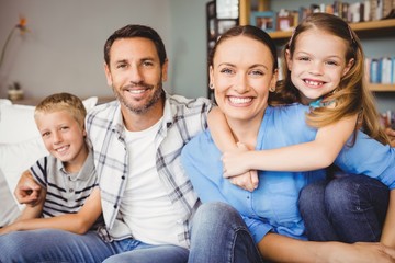 Happy family sitting on sofa against shelf