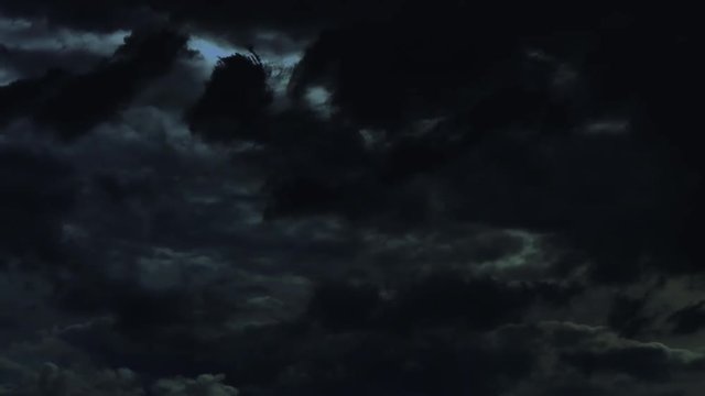 Loopable: Time lapse of clouds during a severe thunderstorm with lightning strikes in the night. The sky becomes darker and lighter over time. Seamless loop.