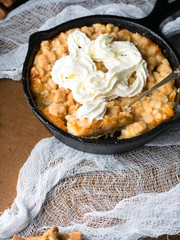 Home made apple crumble with cream. Vertical closeup