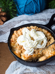 Home made apple crumble with cream in skillet