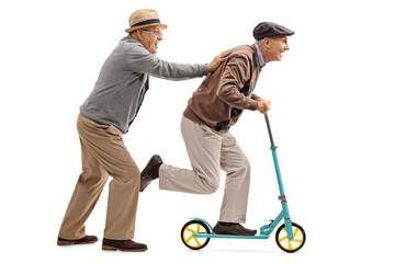Mature man pushing another man on a scooter