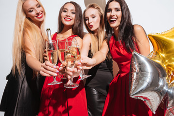 Joyful women clinking glasses and drinking champagne on the party