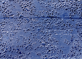 Grungy blue rubber surface with bubbles and scratches.
