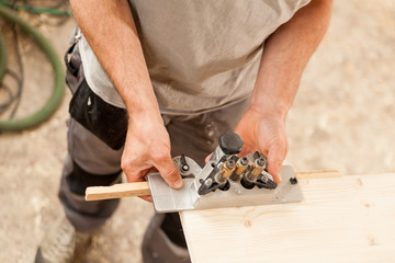woodworker holding a jig on a wooden board