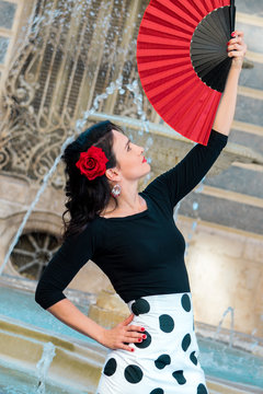 Young beautiful woman in a flamenco costume. Fountain on the background. 