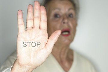 senior woman with her hands signaling to stop over light background