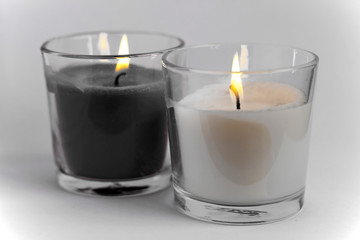 Dos velas encendidas en blanco y negro, con la llama de color