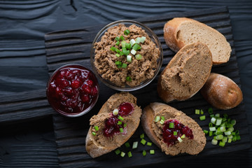 Chicken liver pate with cranberry sauce, black wooden background