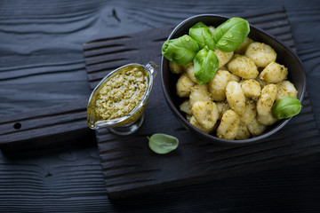 Italian gnocchi with pesto sauce over black wooden background