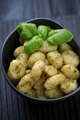 Potato gnocchi with pesto sauce in a ceramic bowl, closeup