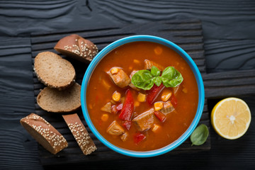 Tomato soup with tilapia fish over black wooden background