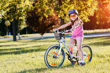 Fototapeta na wymiar happy child girl riding bicycle in summer sunset