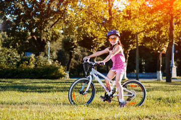 Fototapeta na wymiar happy child girl riding bicycle in summer sunset