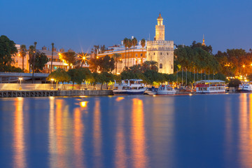 Obraz na płótnie Canvas Dodecagonal military watchtower Golden Tower or Torre del Oro and Guadalquivir river during evening blue hour, Seville, Andalusia, Spain