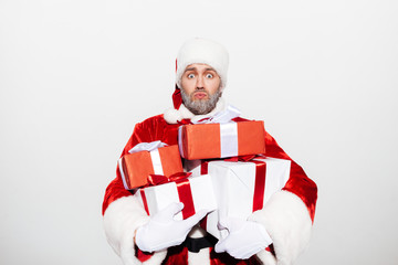 Amazed shocked man santa claus holding pile of gift boxes