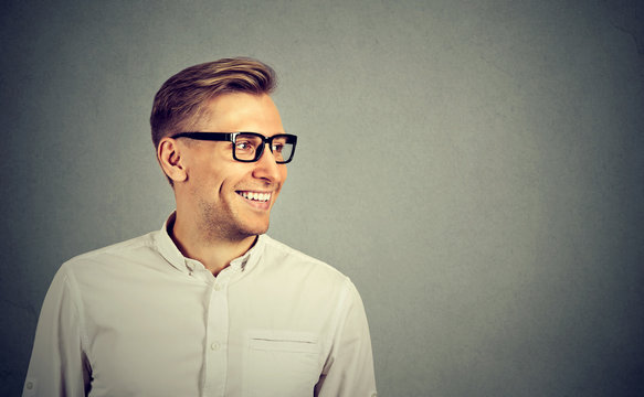 Young man with glasses smiling looking to the side