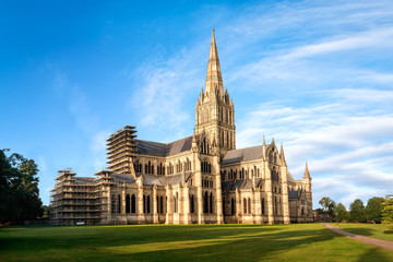 View of Salisbury cathedral church of the Blessed Virgin Mary at sunrise from East. The building is superb example of early english gothic architecture.Copy space in blue sky. - obrazy, fototapety, plakaty