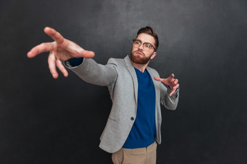 Inspired bearded young businessman in glasses standing and pointing away