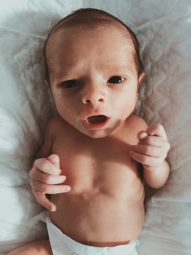 Overhead view of premature baby lying on bed