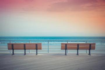 Foto auf Acrylglas Abstieg zum Strand pastellfarbene Strandpromenadenbänke mit Meer und Sonnenuntergang