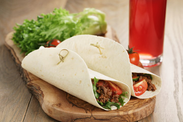 homemade tortilla with beef, frillice and vegetables and drink on wooden board, shallow focus