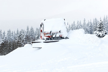 Piste machine (snow cat) covered by snow and ice on mountain ski slope