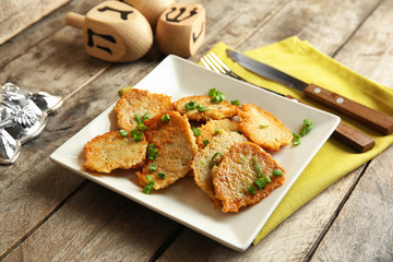 Plate with tasty potato pancakes for Hanukkah on wooden table