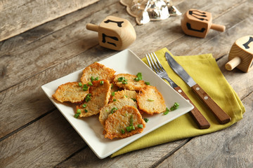Plate with tasty potato pancakes for Hanukkah on wooden table