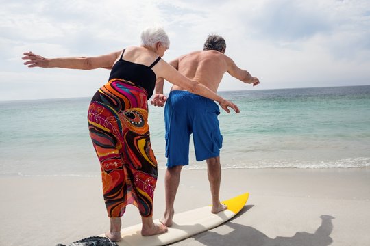Senior couple surfing on beach - Powered by Adobe