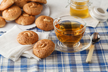Oatmeal cookies with nut, jar with honey  on napkin on brown woo