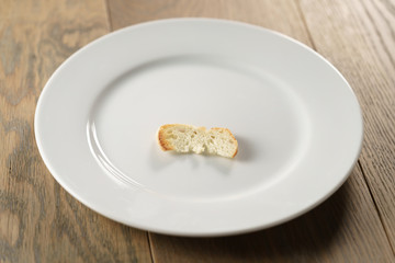 white plate with single dry slice of baguette bread, focus on bread