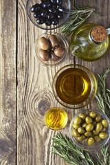 Olives with olive oil and rosemary on the wooden table