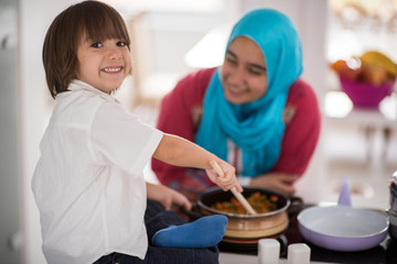 Fototapeta na wymiar Muslim Arabic young mother and little cute son making food and h